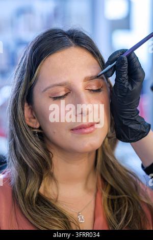 Professionelle Pflege in einem Schönheitssalon konzentriert sich auf Augenbrauenlaminierung, Augenbrauenfärbung, eine junge Frau, Make-up-Artistin, Augenbrauenstyling und eine Kosmetikerin Stockfoto