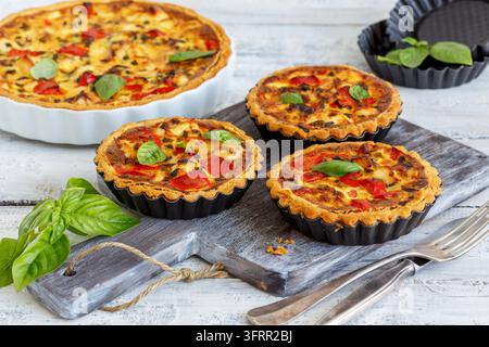 Hausgemachte Mini-Quiche mit Huhn, grünen Zwiebeln und Paprika auf einem alten Holztisch Stockfoto