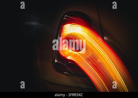 Abstrakte gebogene Lichtspuren von einem leuchtenden Hecklicht eines Autos bei Nacht, absichtliche Kamerabewegung Stockfoto