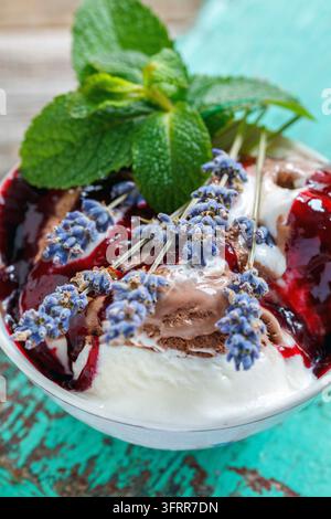 Eis mit Beeren-Topping und Lavendel in der Tasse auf einem alten Tisch Stockfoto
