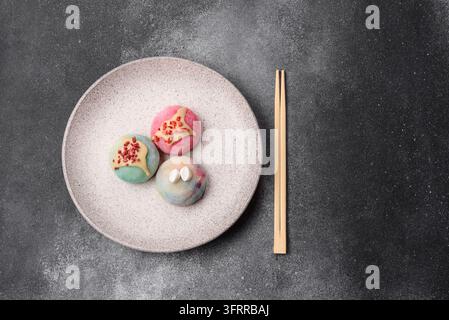 Asiatisches japanisches Mochi-Dessert in verschiedenen Farben und Fruchtgeschmacksrichtungen. Mochi-Dessert als Lebensmittelhintergrund für Ihr Design Stockfoto