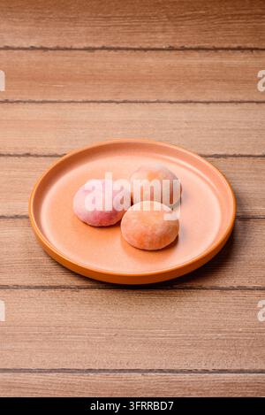 Asiatisches japanisches Mochi-Dessert in verschiedenen Farben und Fruchtgeschmacksrichtungen. Mochi-Dessert als Lebensmittelhintergrund für Ihr Design Stockfoto
