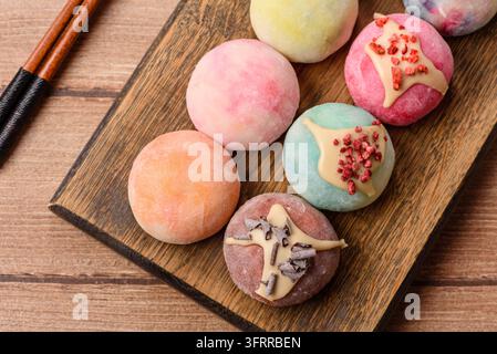 Asiatisches japanisches Mochi-Dessert in verschiedenen Farben und Fruchtgeschmacksrichtungen. Mochi-Dessert als Lebensmittelhintergrund für Ihr Design Stockfoto