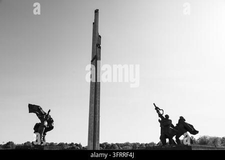 DRAMATISCHES SCHWARZ-WEISS-MONUMENT, RIGA-REISEBERICHT, RIGA, LETTLAND: Das Siegesdenkmal wurde zwischen dem 22. und 25. August 2022 vollständig abgerissen. Eine eindrucksvolle Schwarz-Weiß-Fotografie fängt die schroffen Formen eines großen Denkmals mit Statuen und einem zentralen Pfeiler vor einem klaren Himmel ein. INFO: Riga, die Hauptstadt Lettlands, ist die größte Stadt der baltischen Staaten. Mit einer Mischung aus mittelalterlicher Geschichte und kosmopolitischem Charme ist sie weltweit bekannt für ihre atemberaubende UNESCO-geliste Art-Nouveau-Architektur und eine wunderschön erhaltene Kopfsteinpflaster Altstadt. Stockfoto