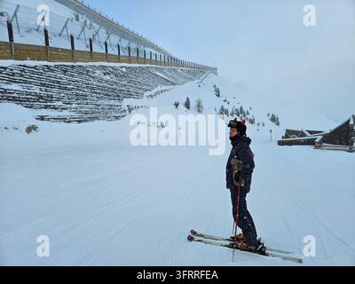 Eine Person steht auf Skiern im Schnee. Der Schnee ist weiß und die Person trägt eine schwarze Jacke Stockfoto