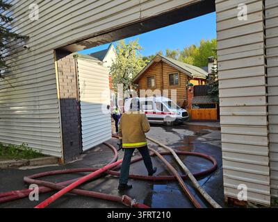 Ein Mann in einer Feuerwehrmann-Ausrüstung geht durch einen Türrahmen. Ein Feuerwehrauto und ein Sanitätswagen sind im Inneren geparkt Stockfoto
