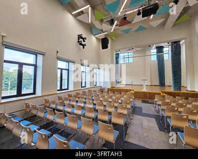 Moskau – 25. Aug., 2025: Großer Saal mit Reihen von Stühlen und einem Podium. Die Stühle sind leer und der Raum ist größtenteils leer in einer renovierten Schule am Tag der offenen Tür Stockfoto