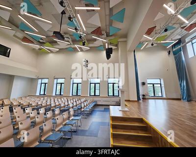 Moskau – 25. Aug., 2025: Großer Saal mit Bühne und Podium. Die Bühne ist leer und die Stühle sind in Reihen angeordnet in einer renovierten Schule am Tag der offenen Tür Stockfoto