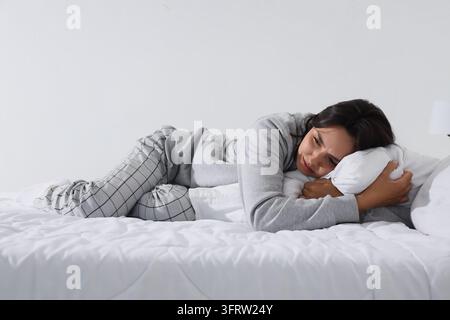 Depression und psychische Probleme, traurige Frau liegt im Bett und fühlt sich einsam und ängstlich mit emotionaler Belastung in einem ruhigen Schlafzimmer zu Hause Stockfoto