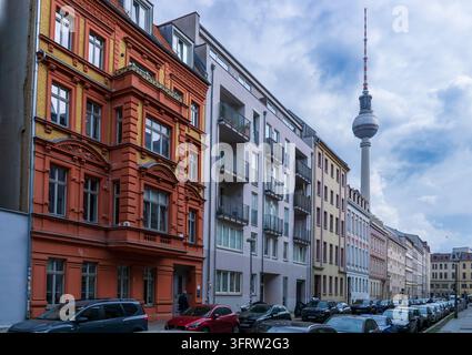 Blick entlang der Almstadtstraße in Richtung Münzstraße in Berlin-Mitte, mit kunstvollen und modernen Wohnfassaden, geparkten Autos und dem Berliner Fernsehturm. Stockfoto