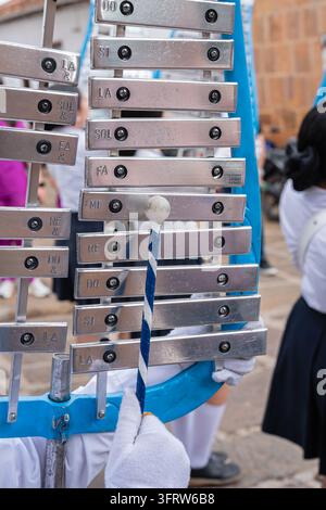 Kindermusiker spielt Glockenspiel in einer Marschkapelle während einer lebhaften Straßenparade, Hände in weißen Handschuhen schlagen mit einem Schläger auf Metallplatten, creati Stockfoto