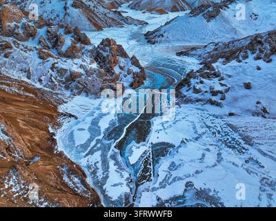 Hochwinkelaufnahme eines langen blauen gefrorenen Sees zwischen schroffen schneebedeckten Schluchtwänden Stockfoto