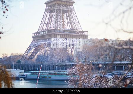 Nahaufnahme von verschneiten Ästen mit verbliebenen Herbstblättern, mit dem Eiffelturm im Hintergrund an einem kalten Wintertag in Paris, Frankreich. Meere Stockfoto