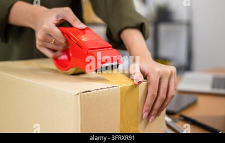 Nahaufnahme Hände einer jungen Frau, die einen großen Karton mit Klebeband verschließt, weibliche Hand packt Box mit Lieferprodukten für Kunden, Kleinunternehmen Start-up Stockfoto