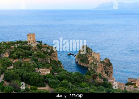 atemberaubender Luftbildblick auf ein Küstendorf mit altem Wachturm und einem Häuschen über einer malerischen felsigen Bucht Stockfoto