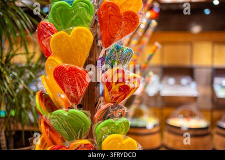 Bunte herzförmige Lutscher, die in transparenter Plastikfolie verpackt sind, werden in einem Süßwarenladen präsentiert. Süße Geschenke und Süßigkeiten zum Valentinstag Stockfoto