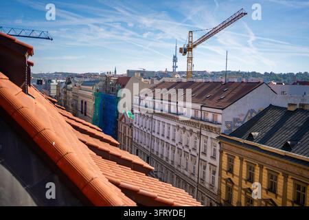 Prag, Tschechische Republik - 01. Oktober 2026: Historische Stadtdächer mit Terrazzofliesen, verzierten Fassaden, Baukränen und entfernter Urbanität Stockfoto