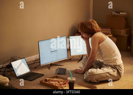 Mann programmiert Software mit mehreren Bildschirmen auf dem Boden zu Hause Stockfoto