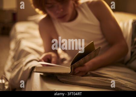 Mann liest Buch im Bett bei Nacht zur mentalen Entspannung Stockfoto