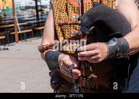Das Bild zeigt einen Musiker, der Dudelsäcke spielt, in traditioneller oder mittelalterlicher Kleidung. Stockfoto