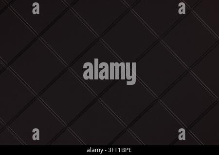 Schwarze Lederoberfläche mit einem luxuriösen gesteppten Diamantmuster, das eine raffinierte dunkle Textur bildet, geeignet für Hintergründe und Polsterdesign Stockfoto