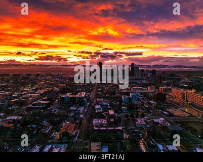 Luftbild der Skyline von Denver bei Sonnenuntergang mit dramatischen orangefarbenen und violetten Wolken über den Stadtgebäuden und den fernen Bergen in Denver, Colorado Stockfoto