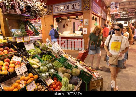 Sevilla Spanien; Menschen kaufen auf einem Obst- und Gemüsestand, Mercado de Triana (Triana-Markt), Innenmarkt in Sevilla (Sevilla), Andalusien, Spanien Stockfoto