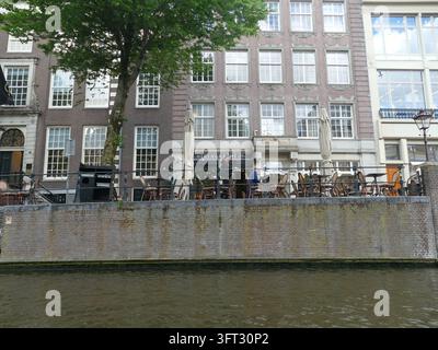 AMSTERDAM - 23. MÄRZ 2025 - Bezauberndes Straßencafé entlang des Herengracht-Kanals in Amsterdam, das eine entzückende Atmosphäre für Kunden bietet, um sich zu entspannen und en Stockfoto