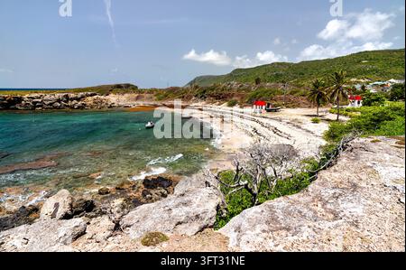 Panoramablick auf die Küste von Anse Baie Mahault mit türkisblauem Wasser, Palmen und Hügeln auf der Insel La Desirade in Guadeloupe. Stockfoto
