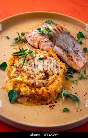 Gebratenes Lachsfilet mit Kürbis- und Süßkartoffel-Rösti-Gratin auf einem Teller serviert Stockfoto