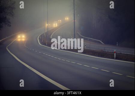 Auto auf der Straße im Nebel. Herbstlandschaft - gefährlicher Straßenverkehr im Winter Stockfoto