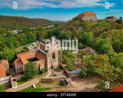 Luftbild des historischen Rosa-Coeli-Klosters in Dolní Kounice, Südmähren, Tschechien. Der mittelalterliche gotische Klosterkomplex ist von üppigen grünen Wäldern und sanfter Landschaft umgeben, mit dem Schloss Dolni Kounice auf dem Hügelgipfel im Stockfoto
