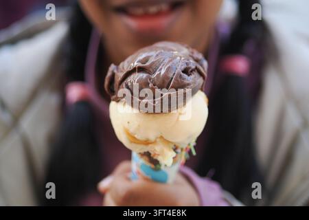 Kind hält eine Eiswaffel mit Schokoladen- und Vanillegeschmack im Park Stockfoto