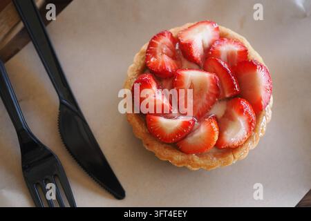 Erdbeertarte, die auf einem Tisch mit Besteck in der Nähe platziert ist Stockfoto