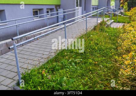 Zugänglicher Rampenweg mit Geländern führt zum Gebäudeingang Stockfoto