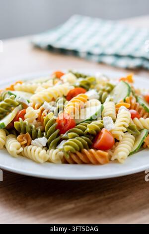 Bunte Fusilli-Pasta-Salat mit frischen Gemüsen und Fetakäse auf Holztable Stockfoto