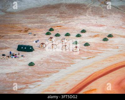 Luftbild eines Campingplatzes mit mehreren aufgestellten Zelten auf der einzigartigen rot-weiß geschichteten Landschaft von Kyzyl Kup im Bezirk Karakiya, Region Mangystau Stockfoto