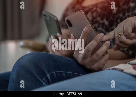 Nahaufnahme einer Gruppe erwachsener Freunde, die auf einem Sofa sitzen und mit den Händen ein modernes Smartphone benutzen. Konzept für gemeinsames Arbeiten. Selektiver Fokus. Stockfoto