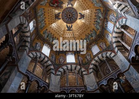 INTRIKATER GOLDENES MOSAIKKUPPEL, AACHENER DOM, AACHEN, DEUTSCHLAND: Ein direkter Blick nach oben auf das atemberaubend detaillierte goldene Mosaik an der oktogonalen Kuppeldecke der historischen alten Kathedrale. INFO: Der Aachener Dom, Deutschlands erstes UNESCO-Weltkulturerbe, ist ein karolingisches architektonisches Meisterwerk, das von Karl dem Großen gegründet wurde. Diese historische Sehenswürdigkeit, die byzantinische und gotische Elemente vereint, diente als Krönungskirche für einunddreißig deutsche Monarchen. Stockfoto