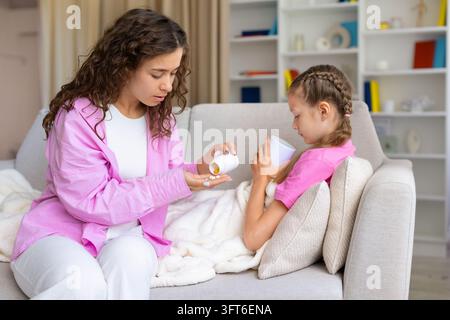 Besorgte Mutter gießt Medizin in ihre Hand, um sie ihrem kranken Kind zu verabreichen Stockfoto