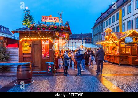 Bamberg, Deutschland – 28. November 2025. Menschen an einem beleuchteten Churro-Stand auf dem Bamberger Weihnachtsmarkt. Stockfoto
