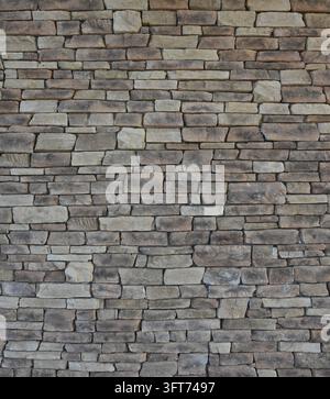 Flache Steinwand mit unterschiedlichen rechteckigen Steinen in einer vertikalen Komposition, die poröse hellbraune, weiße, hellgraue und bunte Färbungen aufweist Stockfoto
