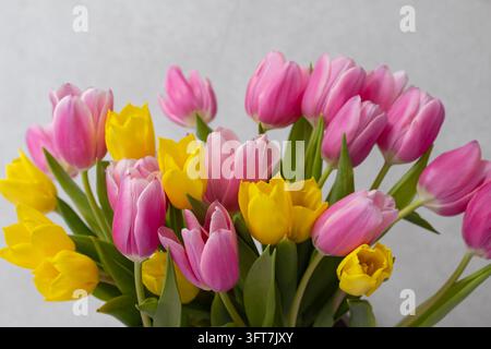 Wunderschönes Bouquet aus rosa und gelben Tulpen auf weichem neutralem Hintergrund Stockfoto