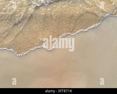 Sanfte Meereswelle, die über einen glatten Sandstrand spült, Luftaufnahme Stockfoto