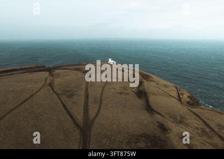 Luftaufnahme des Duncansby-Head-Leuchtturms auf einer schroffen Klippenkante mit Blick auf die Nordsee, mit grasbewachsenem Gelände und Feldwegen, John o' Groats, Highlan Stockfoto