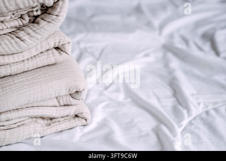 Rand eines zerknitterten Baumwollgazeflors neben glattem Laken, Stoff, der kein Bügeln benötigt und Zeit bei der Haushaltswäsche spart Stockfoto