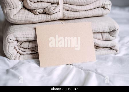 Nahaufnahme einer leeren Papierkarte vor einem gestrickten Baumwollgazenstapel, Vorlage für Ladenschilder und Werbung in Leinenläden Stockfoto