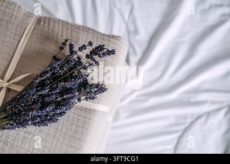 Bündel getrockneter Lavendel, der auf zerknittertem Baumwollgaze neben weichem Laken ruht, beruhigendes Kraut, das oft mit natürlichen Schlafroutinen in Verbindung gebracht wird Stockfoto