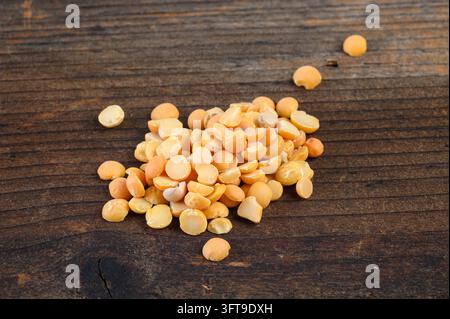 Haufen roher gelber gespaltener Erbsen auf einem alten dunklen Holztisch. Stockfoto