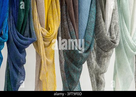 Bunte leichte gestrickte Schals, die in Reihen mit zarten Openwork-Mustern hängen Stockfoto
